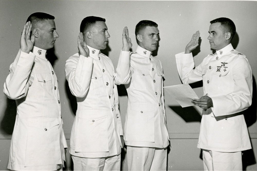 mystery photo of three uniformed students taking an oath from a fourth student