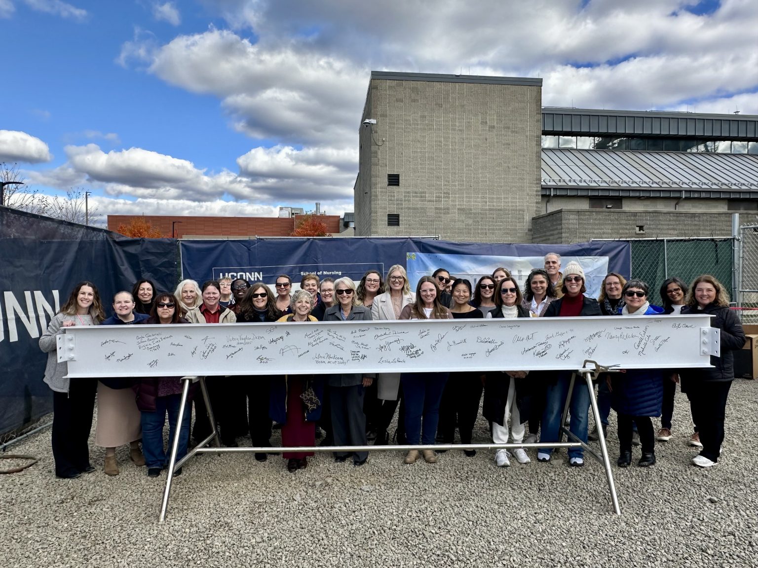 Elisabeth DeLuca School of Nursing faculty and staff at the beam signing ceremony on October 27, 2025 posing behind the signed beam